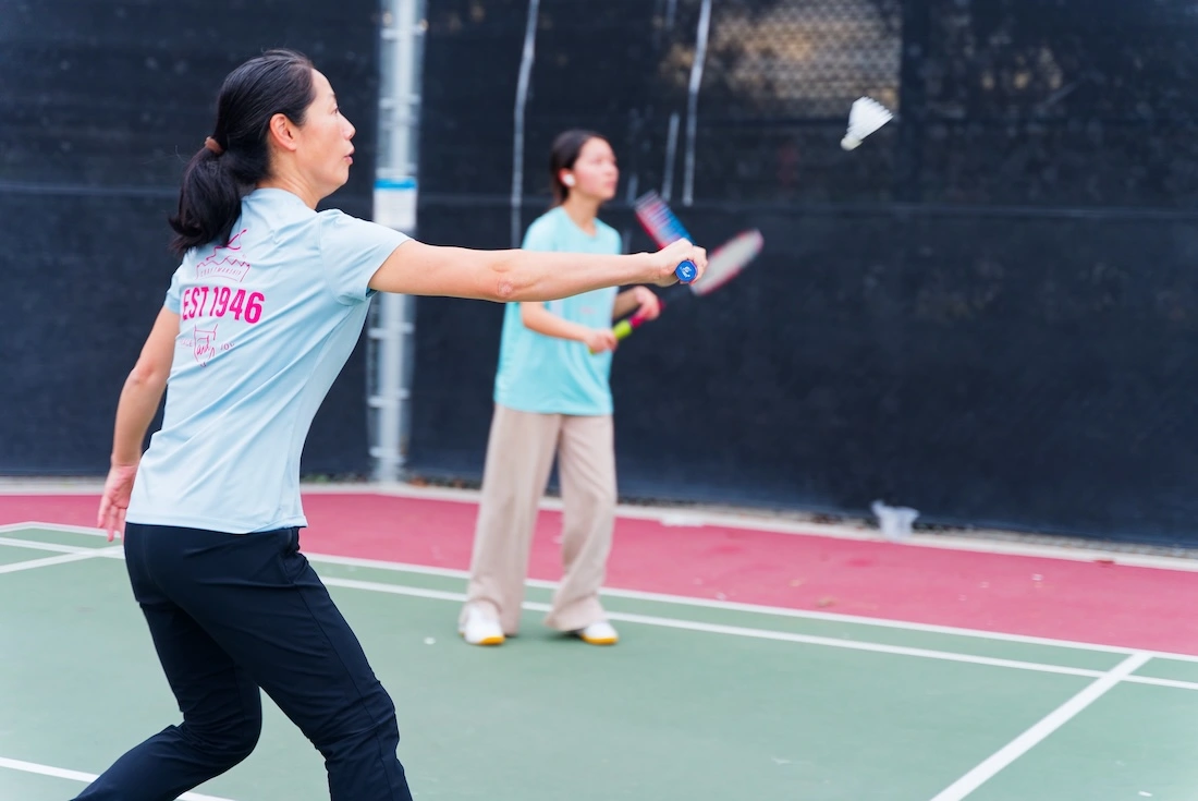 Two badminton players moving through a fast rally